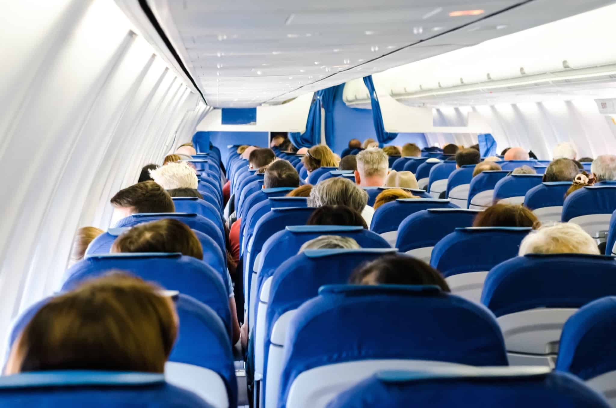 pessoas sentadas num avião com assentos azuis