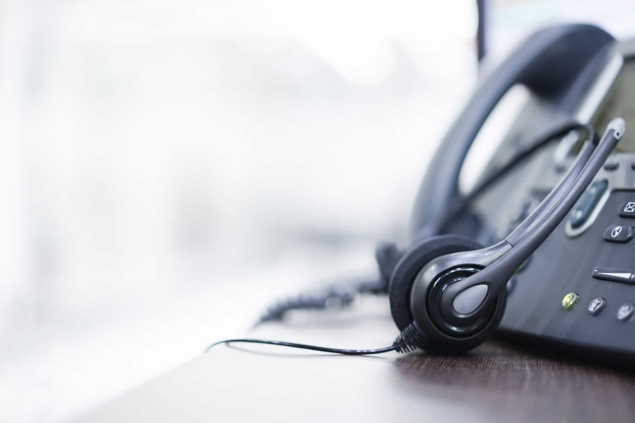 telefone preto com uns headphones ao lado