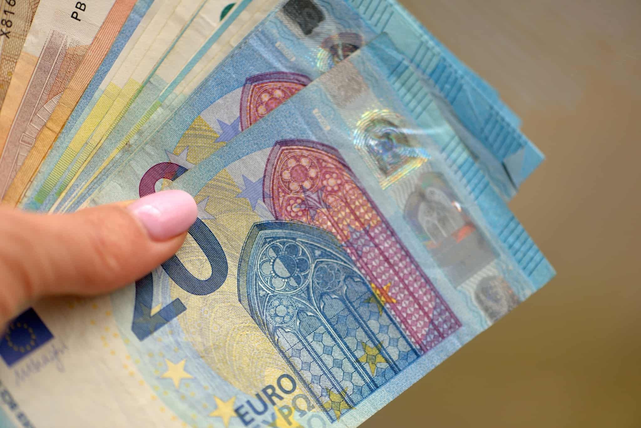 mulher de unha cor de rosa a segurar notas de vinte e dez euros