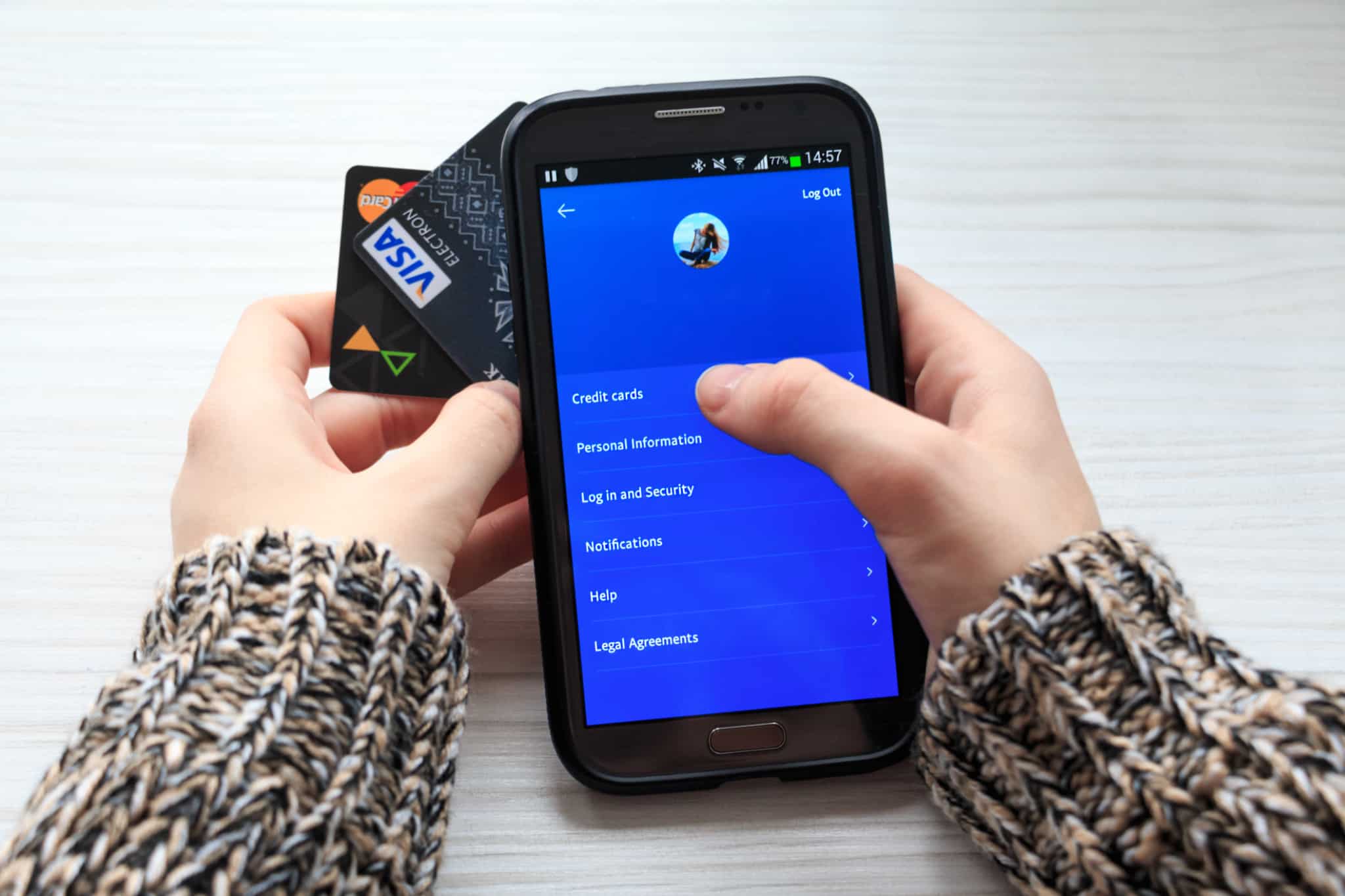 pessoa com cartões de crédito a mexer numa app de fundo azul