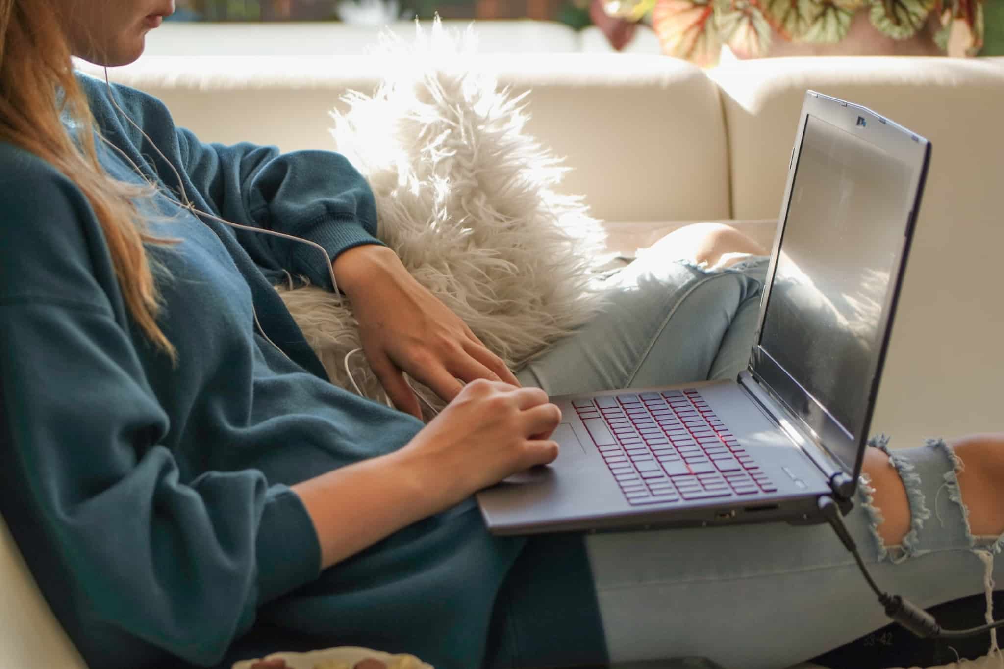 jovem sentada no sofá a mexer no computador portátil