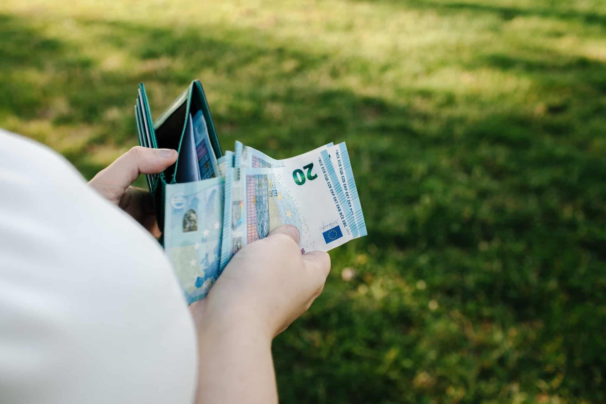pessoa a tirar notas de vinte euros da carteira