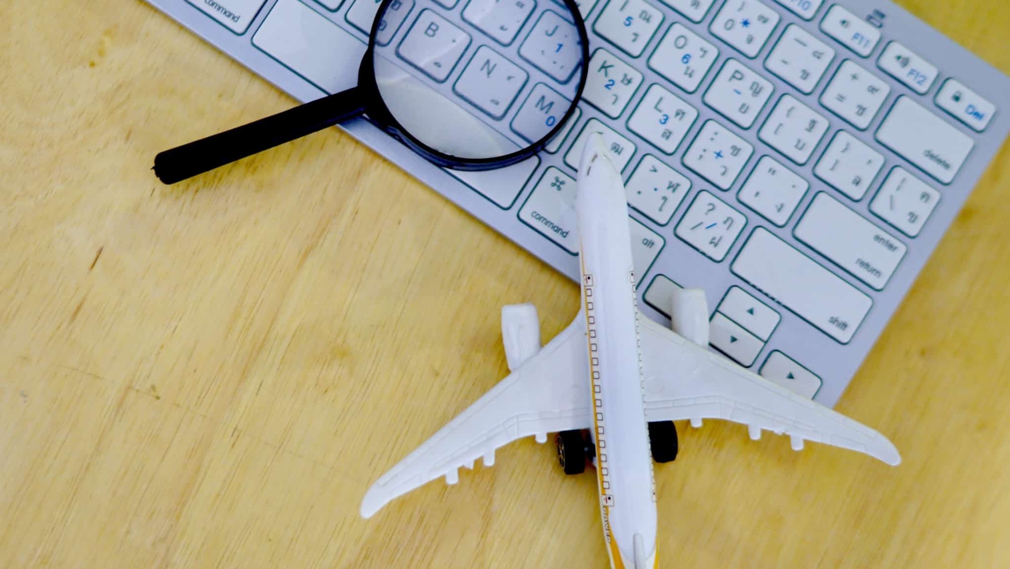teclado de computador com uma lupa e um avião em cima