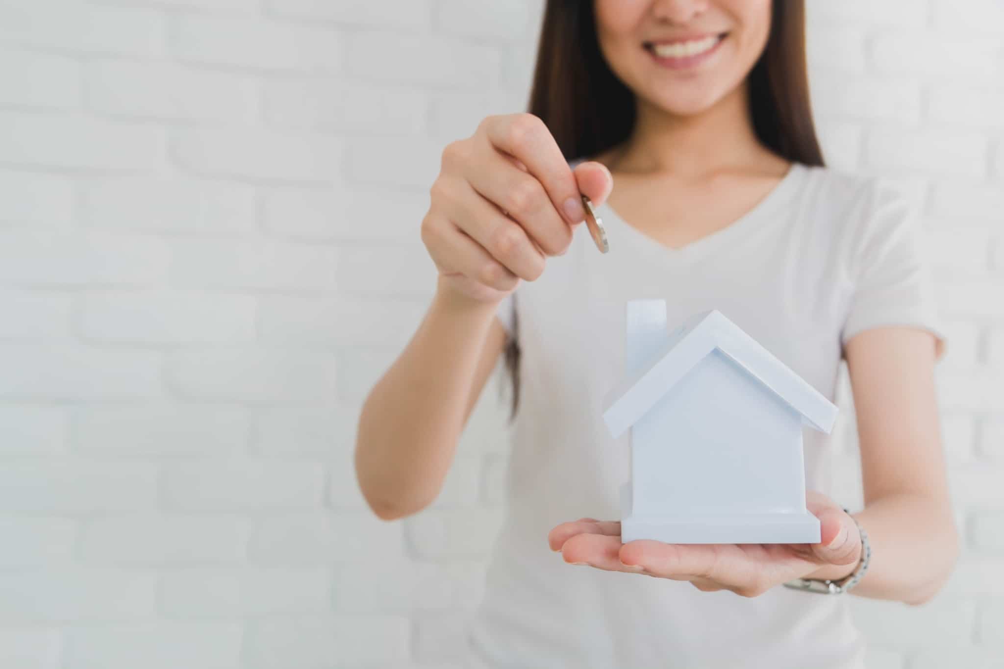 mulher com casa na mão e a colocar a moeda