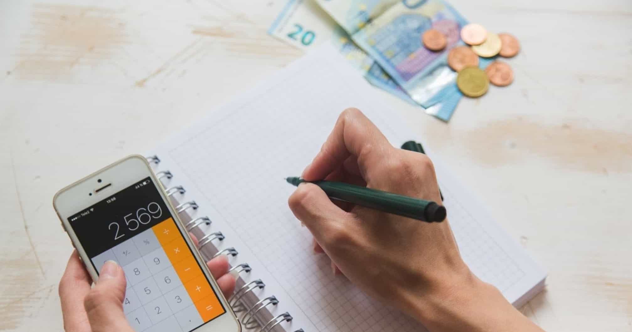 pessoa a fazer contas com um telemóvel e dinheiro