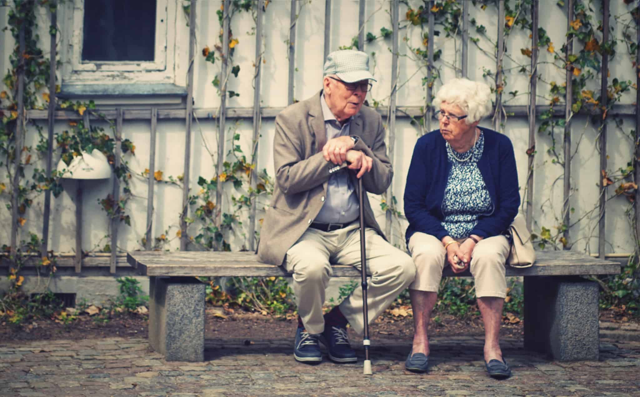 casal de idosos sentados no banco a conversar