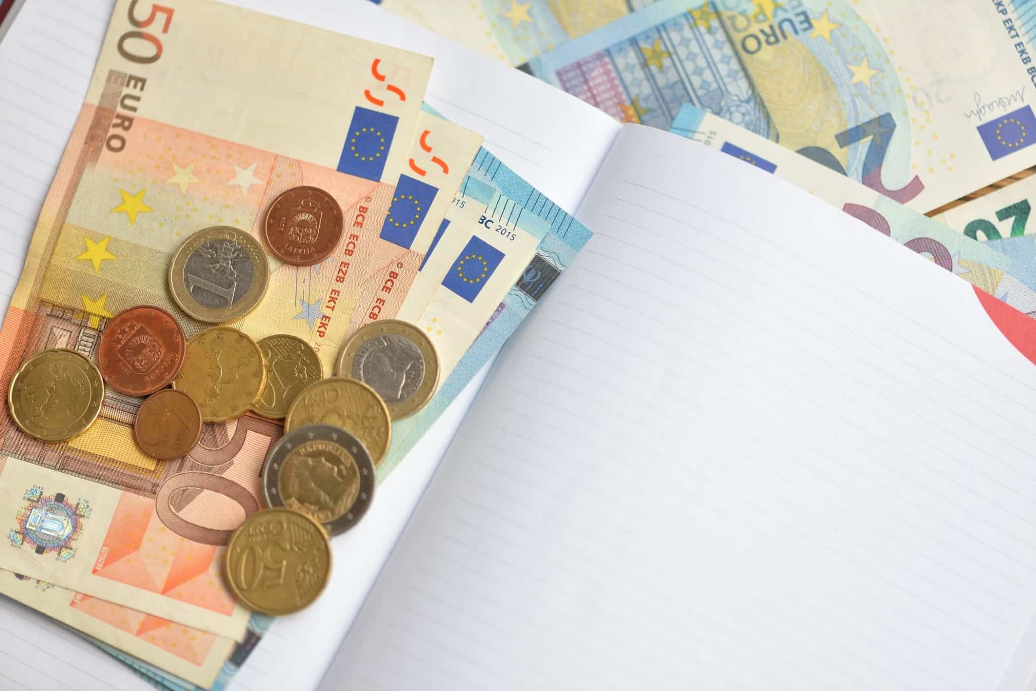 notas e moedas de euros dentro de um bloco de notas