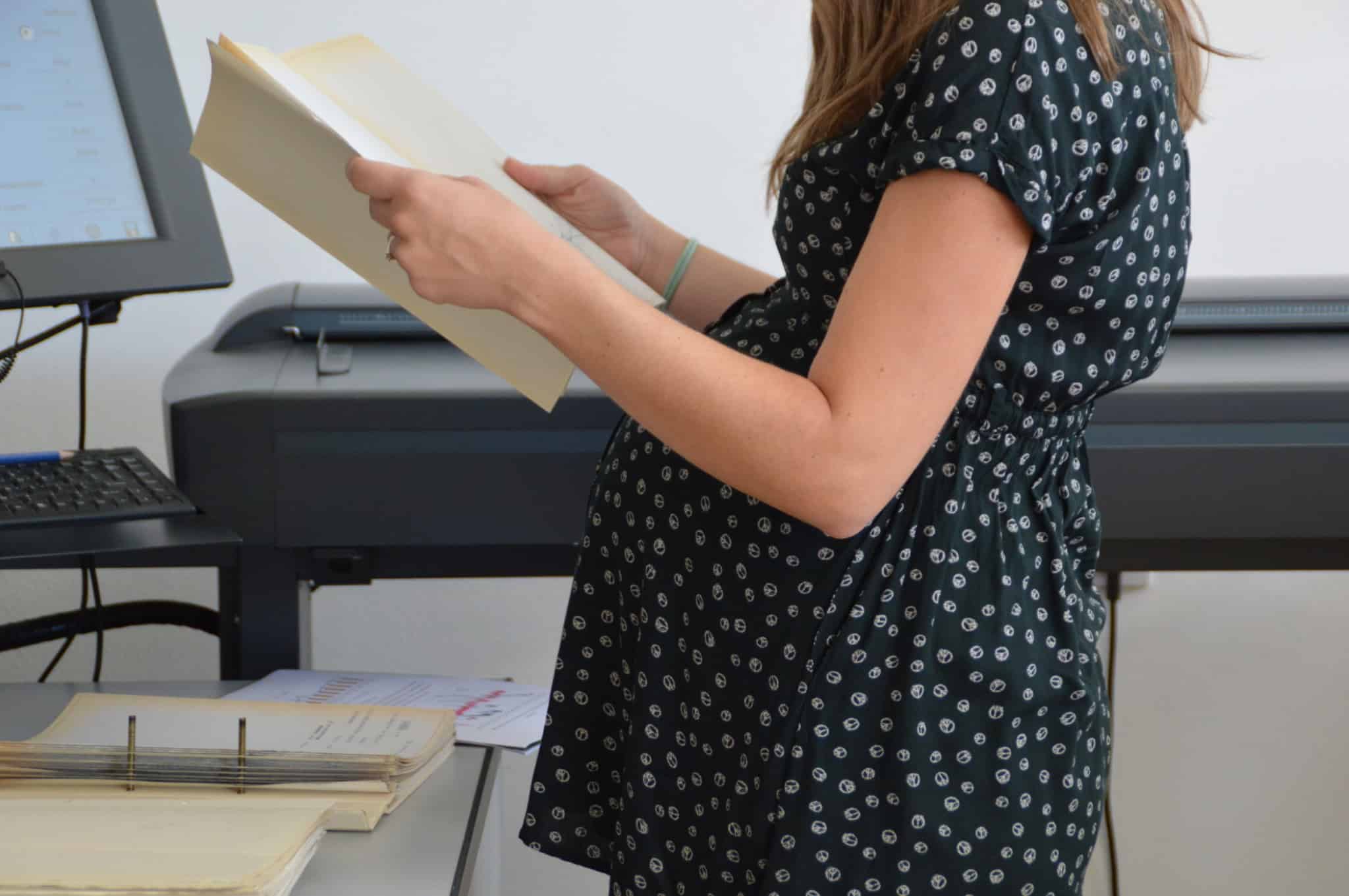 mulher grávida com vestido às pintinhas a segurar numa pasta