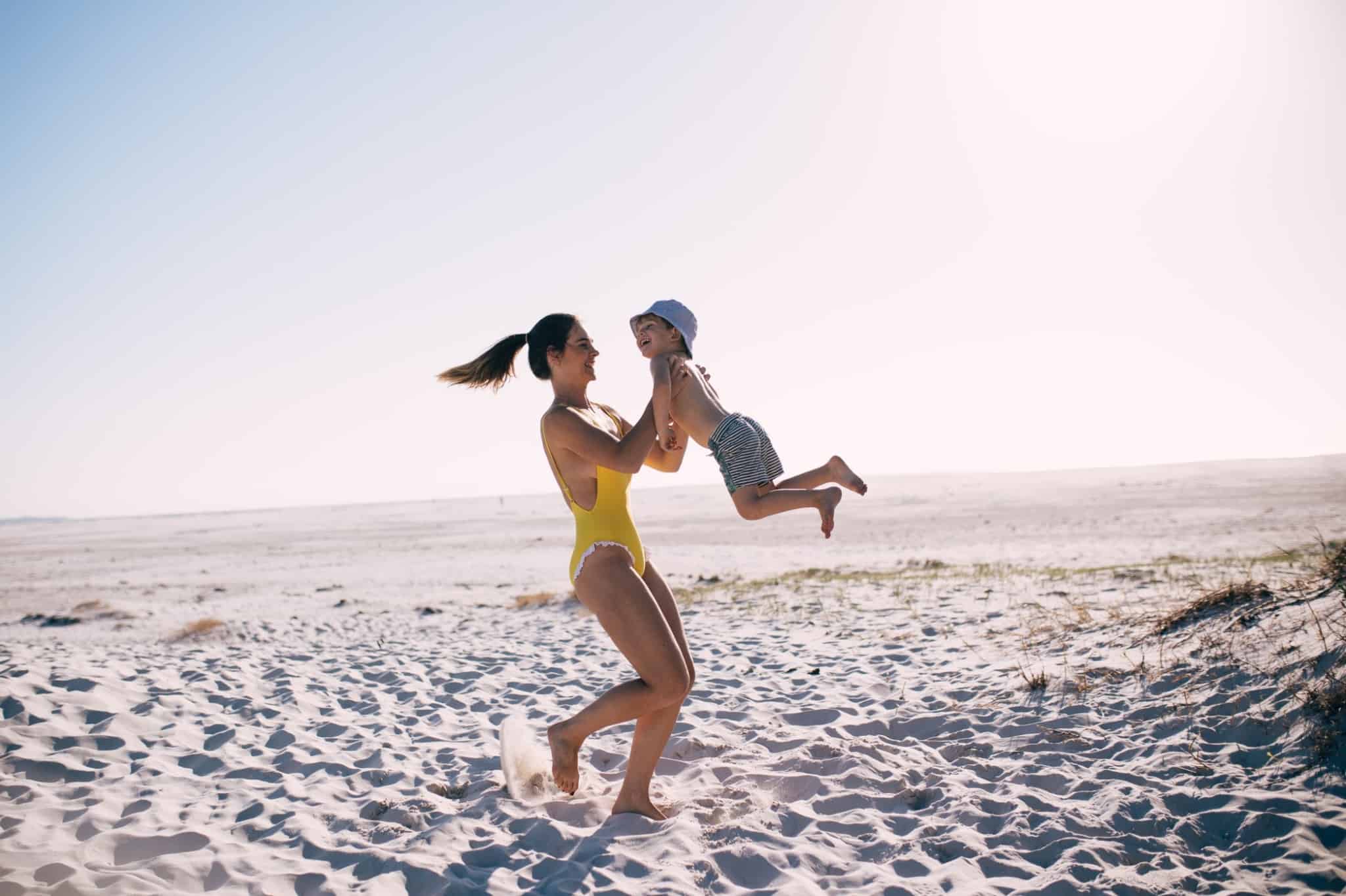 mulher a carregar um filho na praia