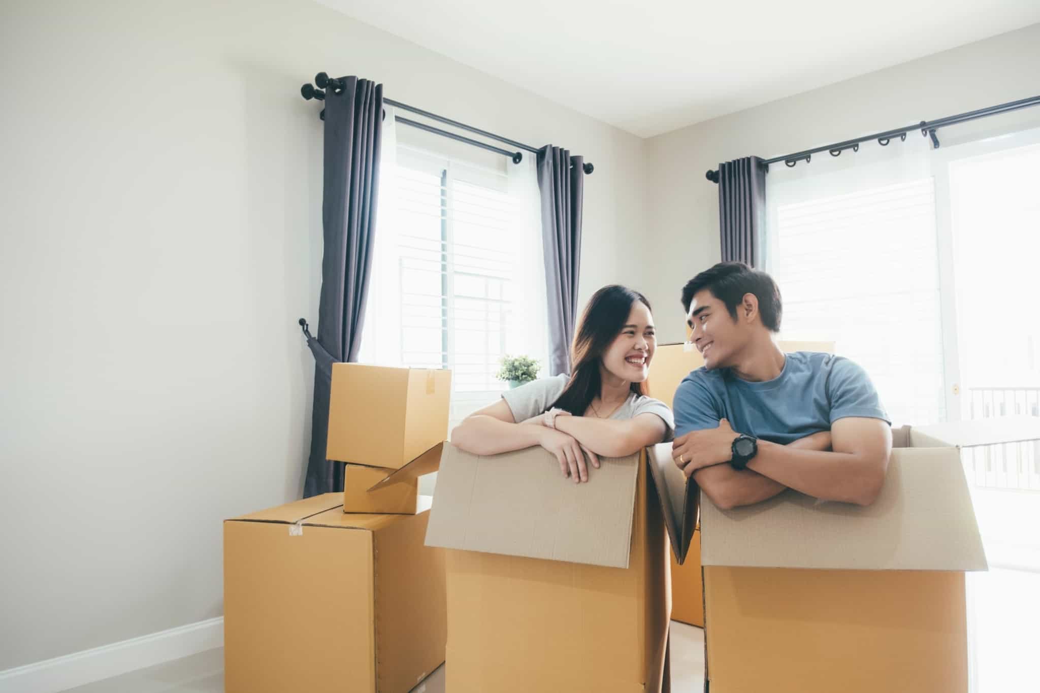 casal dentro de caixas de cartão a fazer mudanças em casa