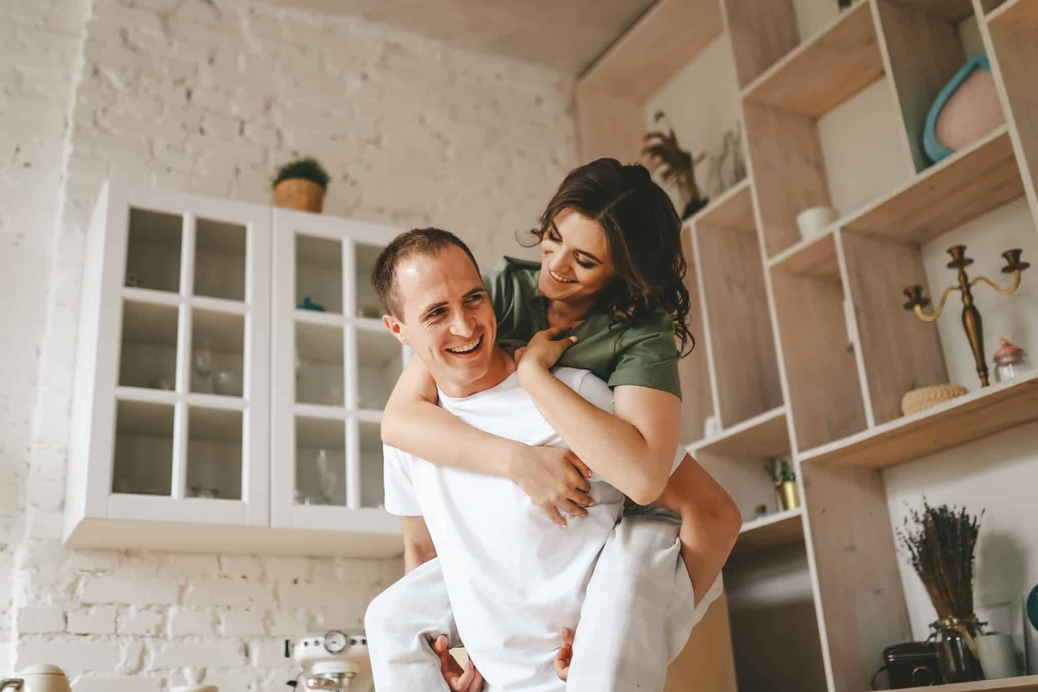casal feliz dentro de casa com a mulher às cavalitas