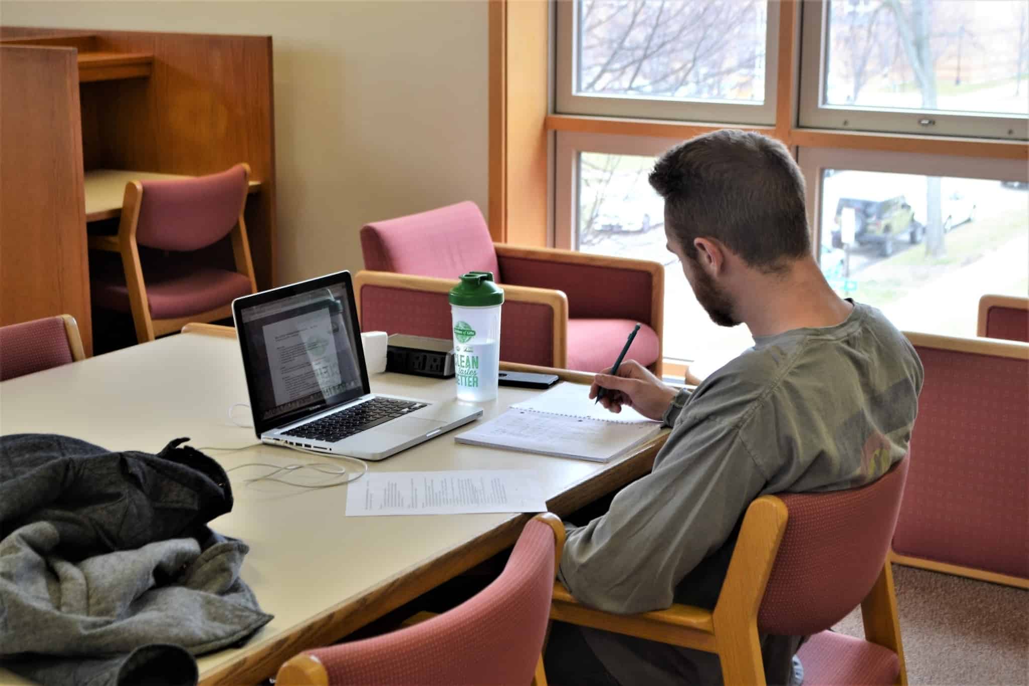 rapaz estudante a trabalhar na biblioteca
