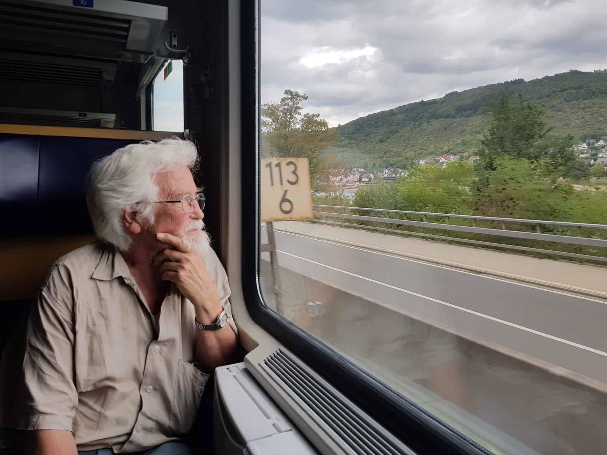 pessoa mais velha de cabelo branco a olhar para a janela dentro de um comboio
