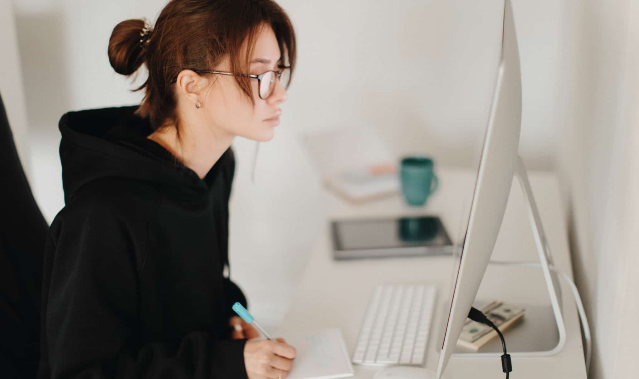 Jovem no computador e a fazer apontamentos