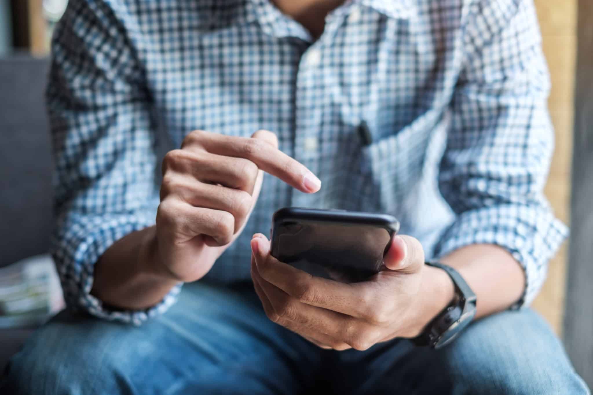 pessoa a mexer no telemóvel e a apontar o dedo indicador
