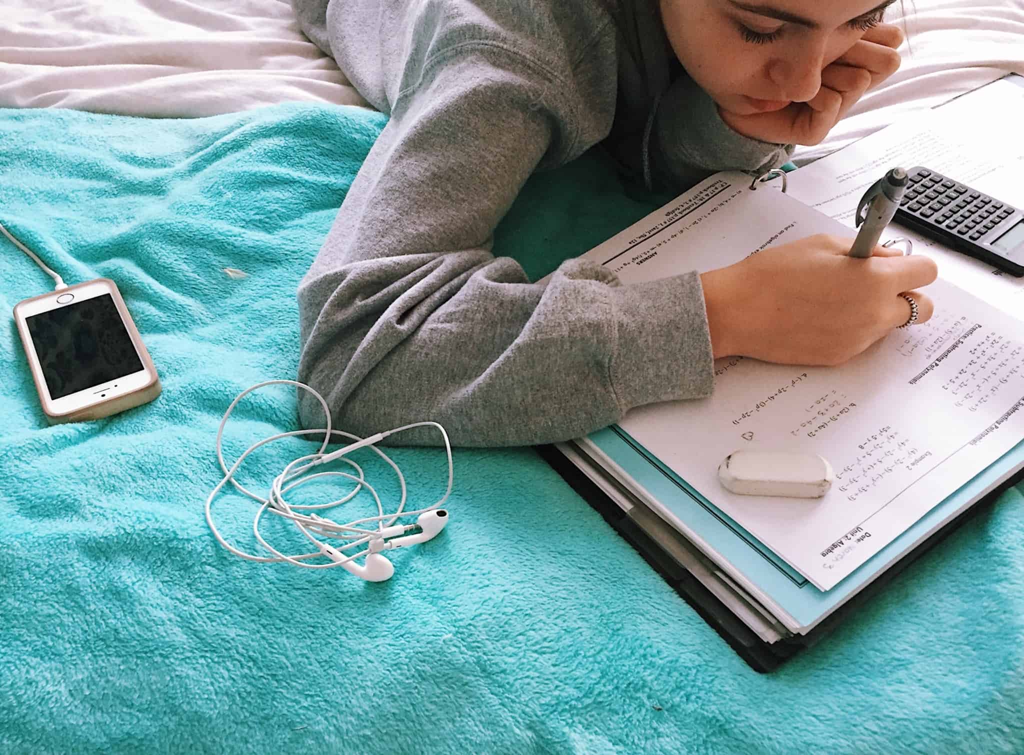 criança em cima da cama a fazer os trabalhos de casa de matemática