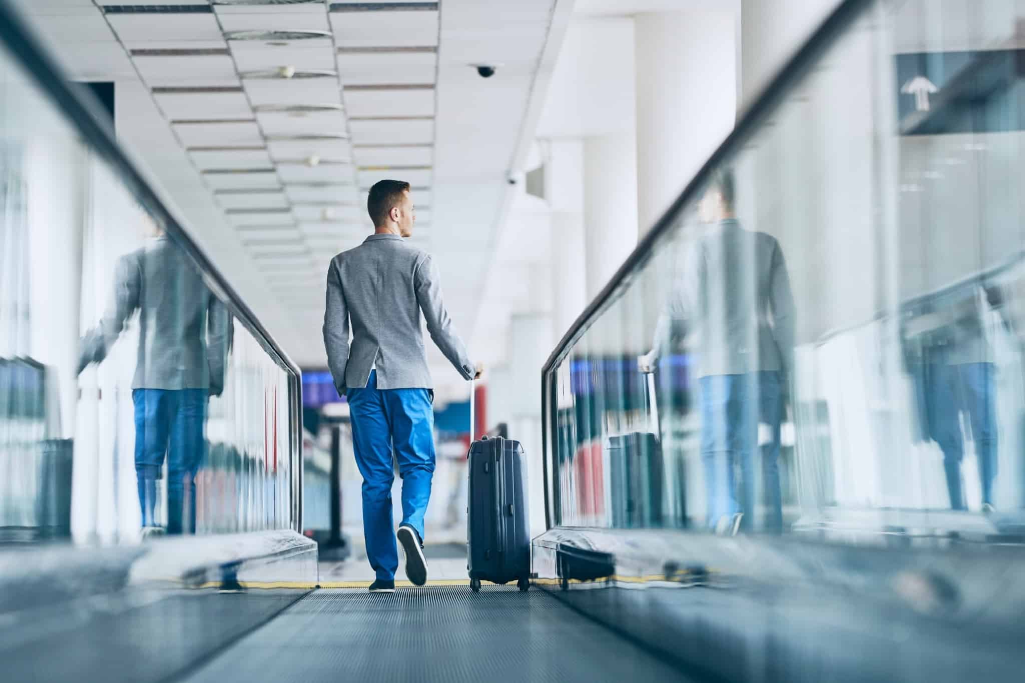 homem de blazer cinzento a andar nas escadas rolantes de um aeroporto