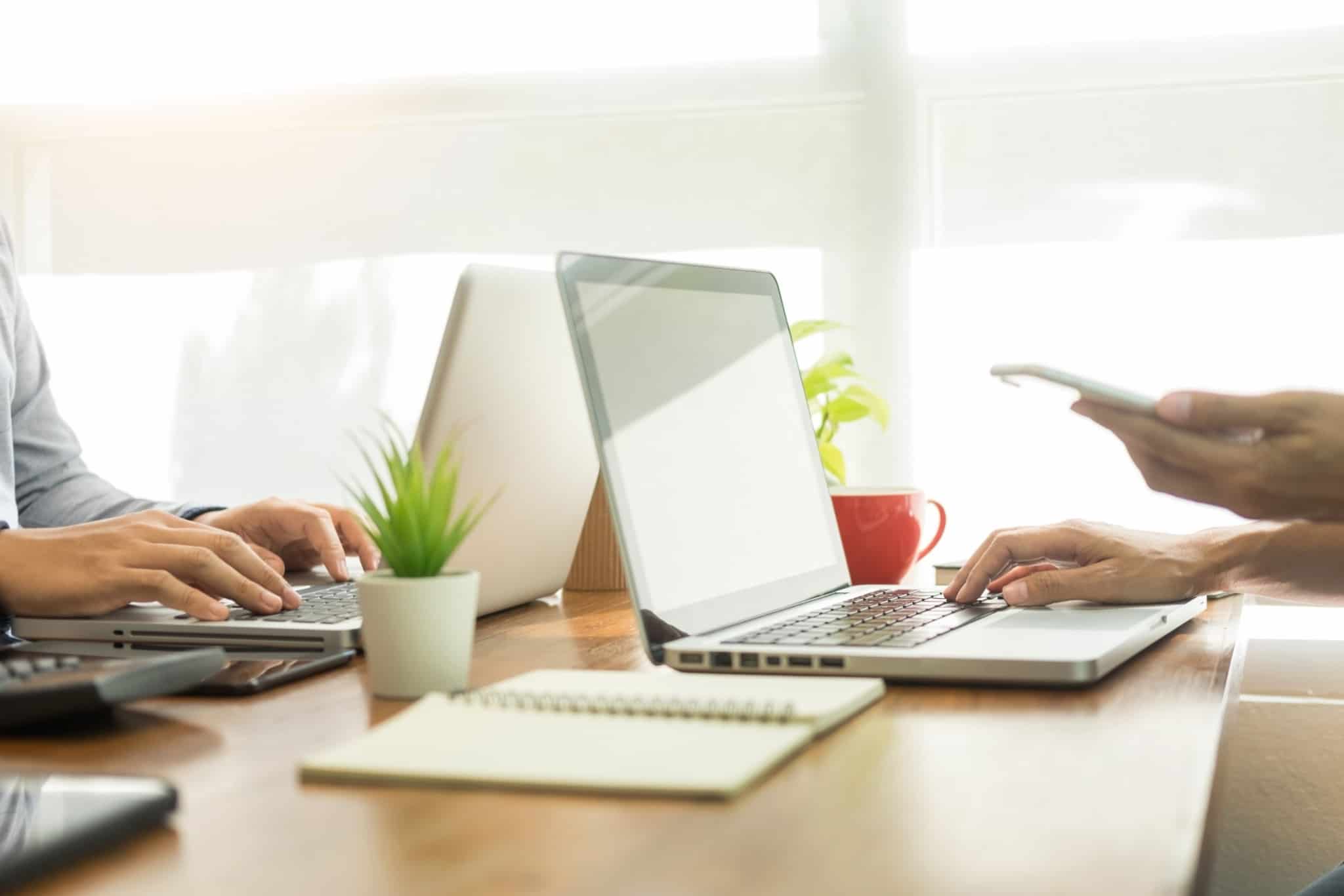 dois computadores e pessoa a agarrar telemóvel