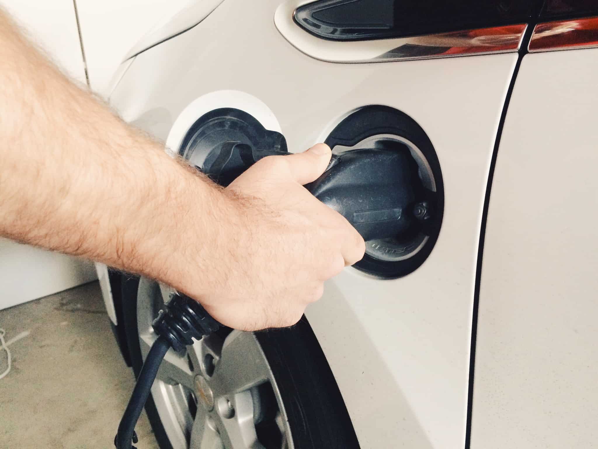 Mão de um homem a pôr o carro elétrico a carregar