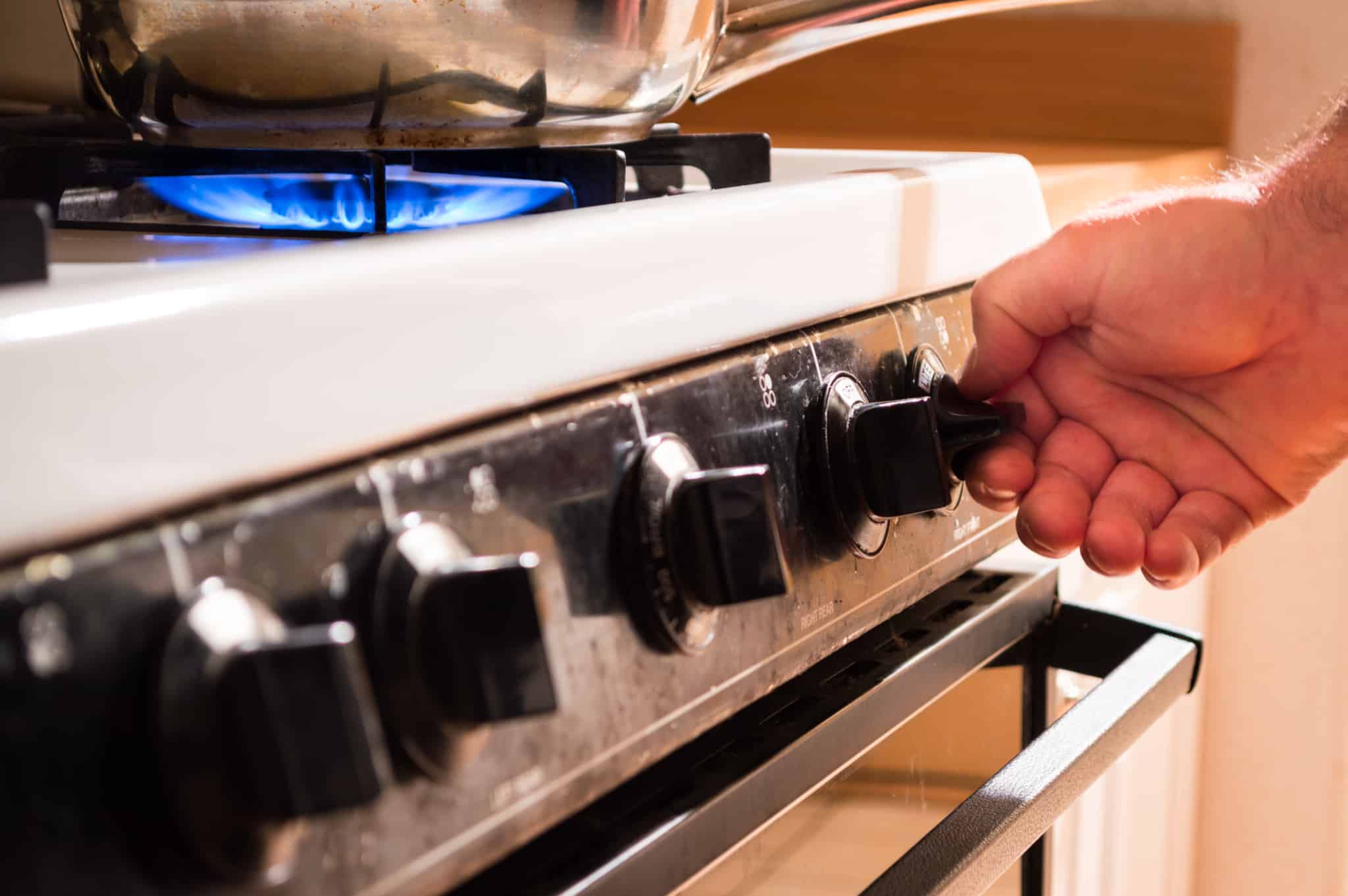 Mão a ligar o fogão a gás para cozinhar