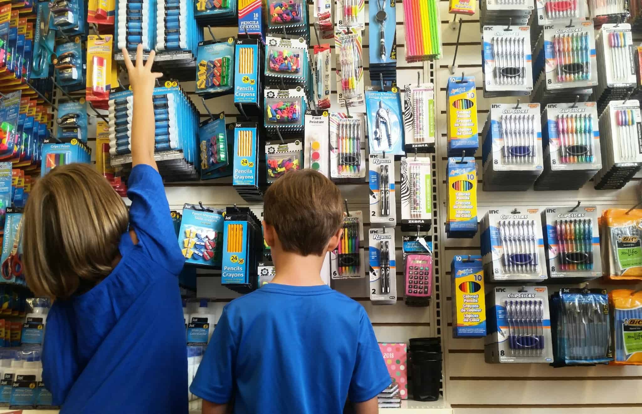 Duas crianças a escolheres material escolar, como canetas, lápis e borrachas