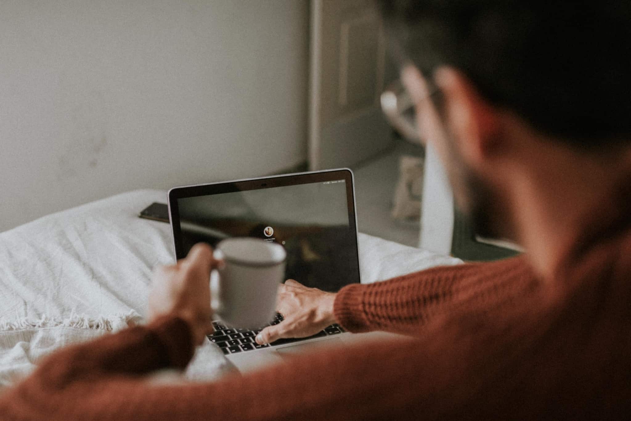 homem a mexer no computador com uma caneca de café