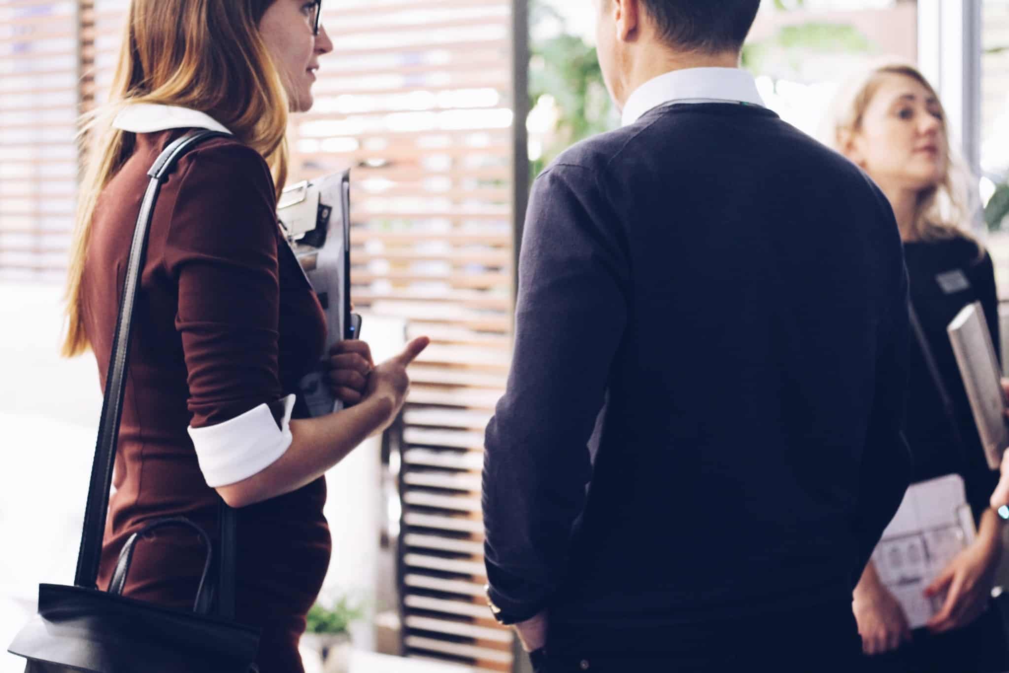 dois colegas de trabalho a conversar à porta de uma sala
