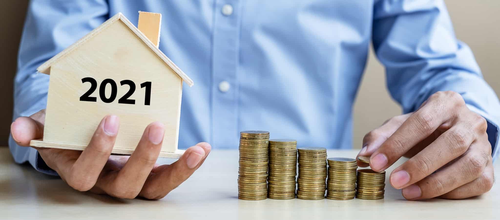 Pessoa a segurar uma casa com 2021 estampado e a organizar moedas