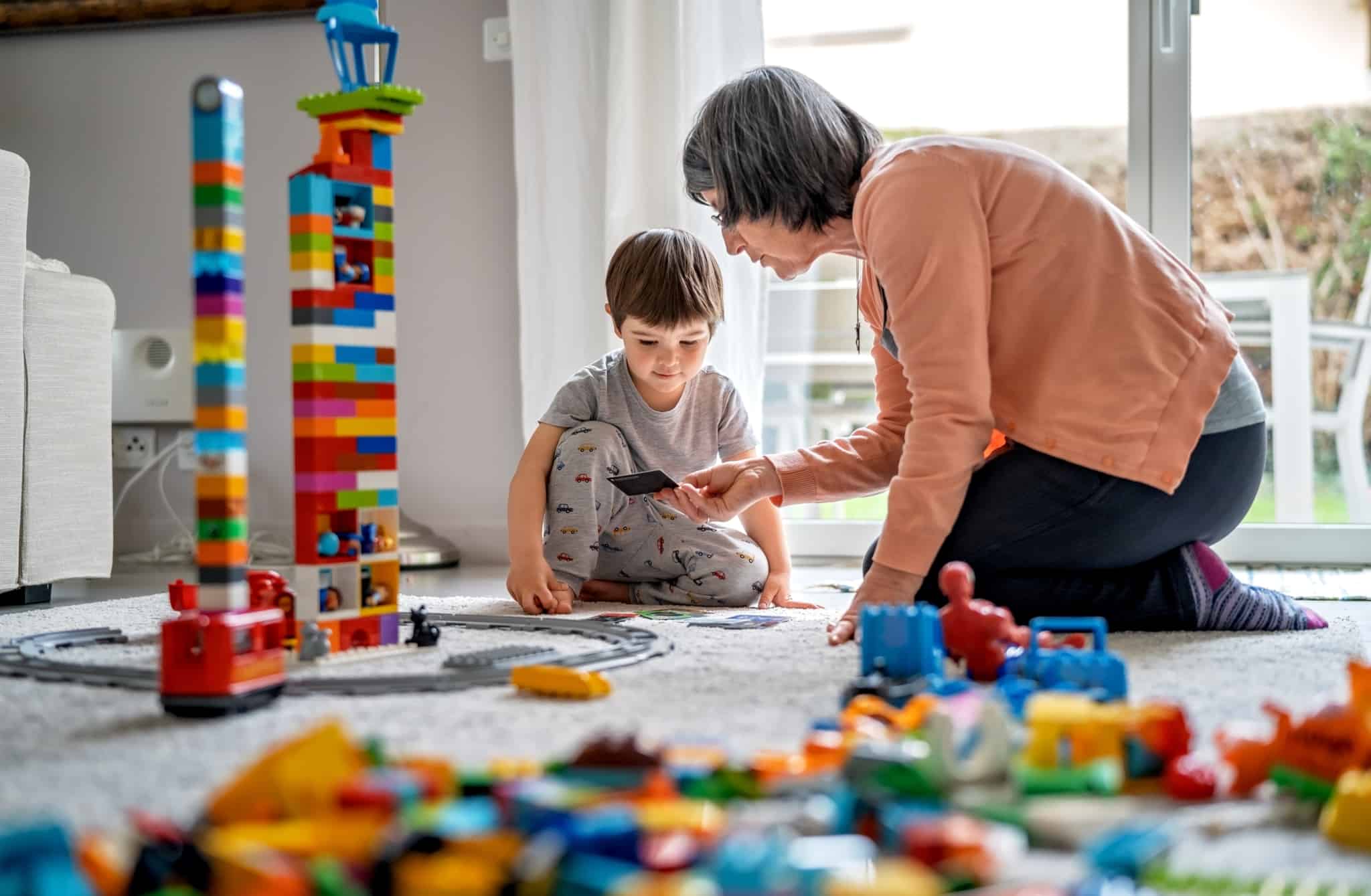 Criança a fazer construções com legos no seu quarto com a avó