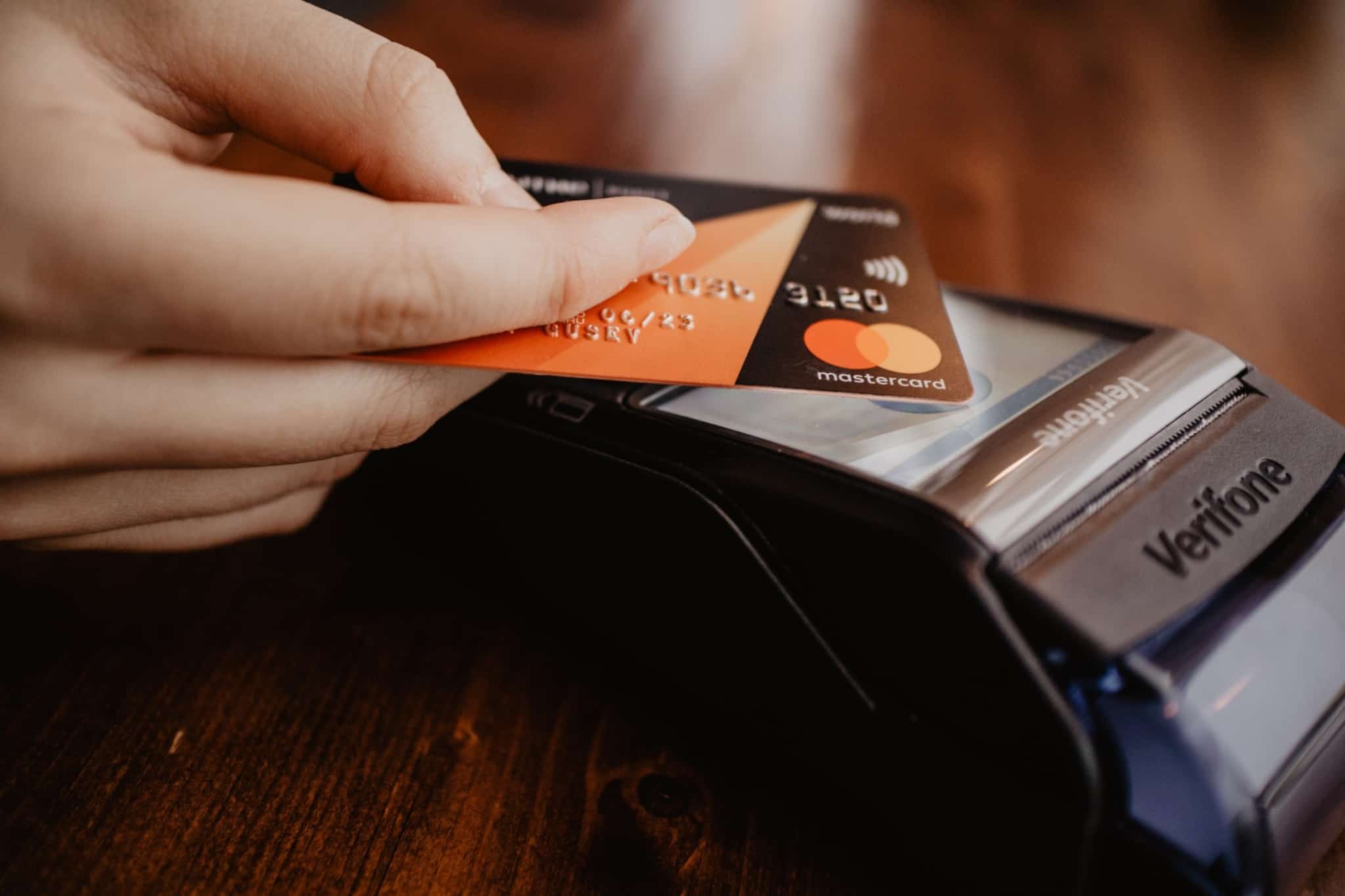 pessoa com um cartao preto da mastercard a fazer uma compra no terminal de pagamento