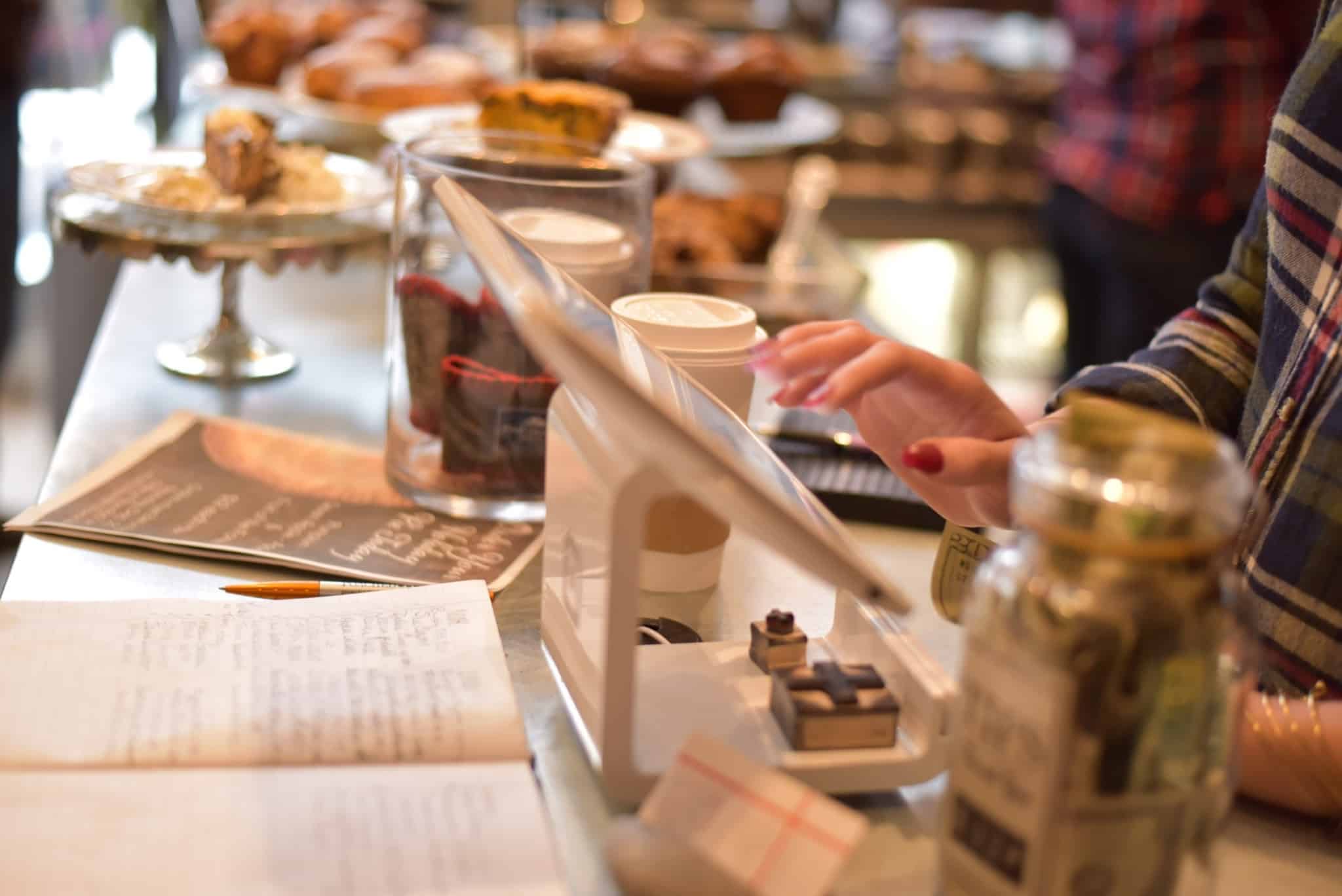 Balcão de café ou pastelaria, onde se pode ver alguém a usar a caixa registadora