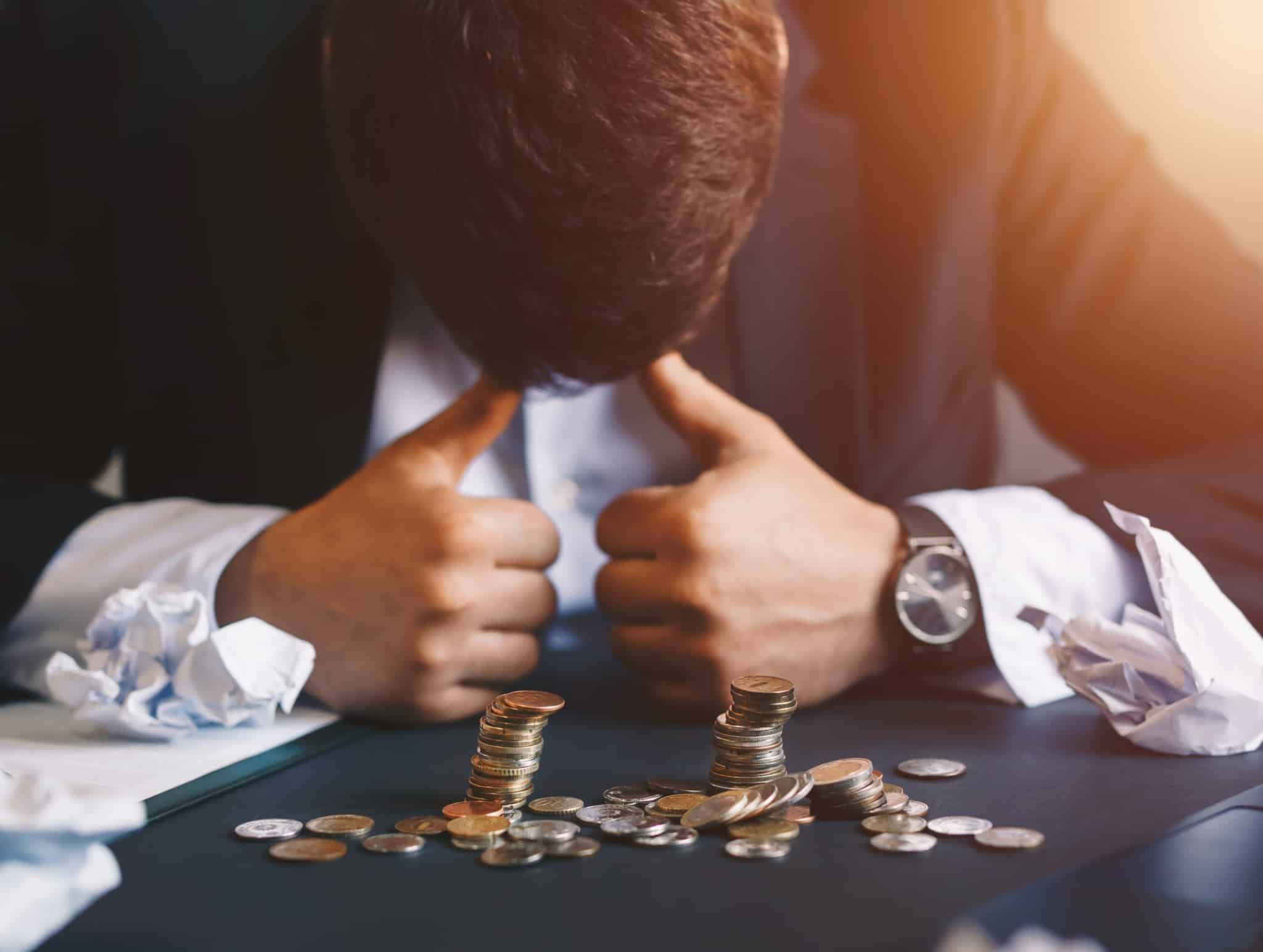 Homem com cabeça em baixo e moedas caidas