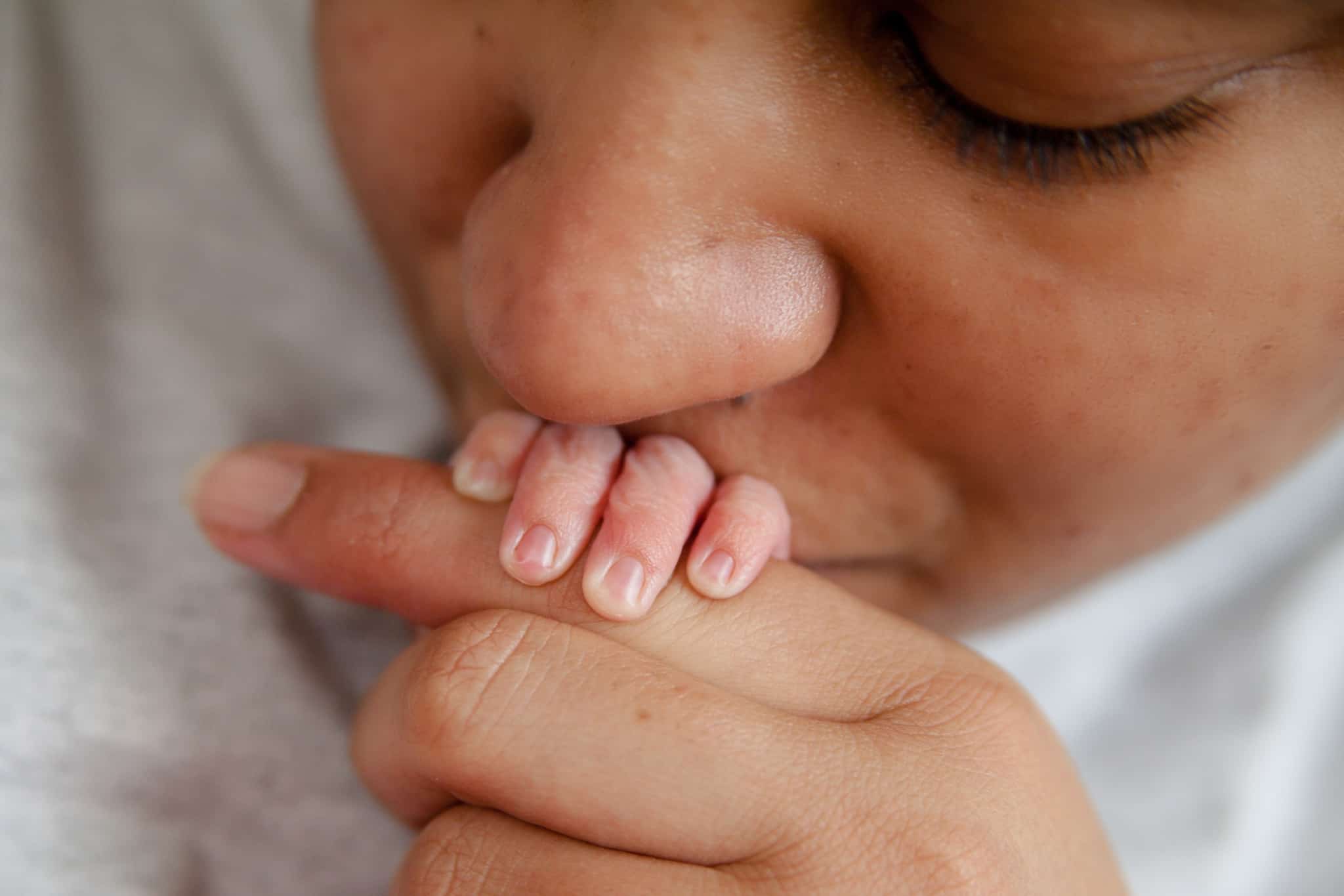 Mãe a dar um beijo na mão de um recém-nascido