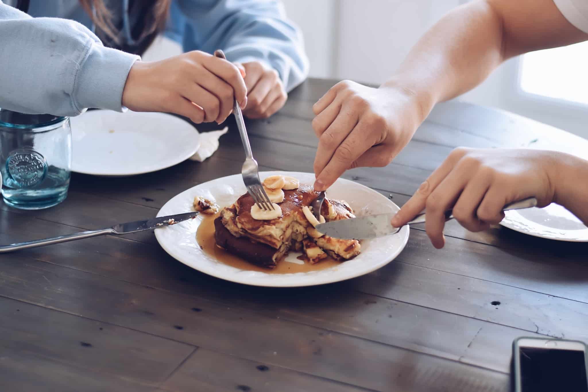 duas pessoas em co-living a partilhar panquecas ao pequeno almoço
