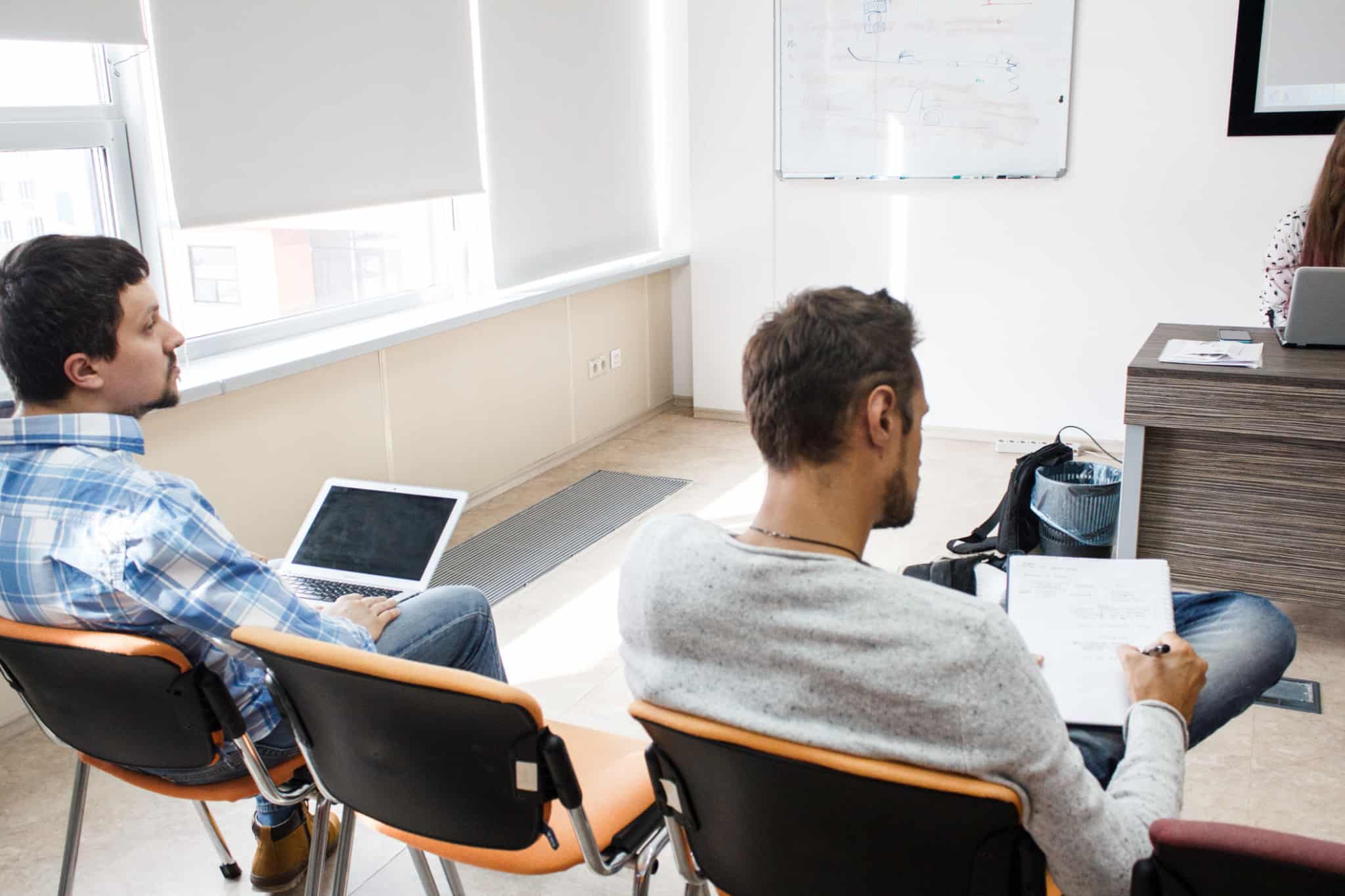 Dois jovens sentadas com computadores e cadernos, durante uma aula