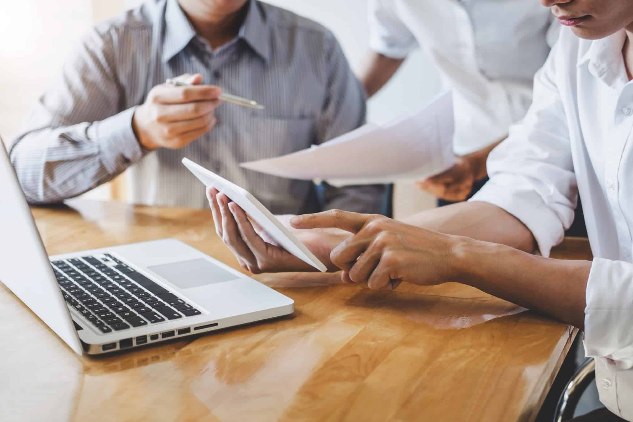 Pessoas a trabalharem em conjunto em frente a um computador e a rever algumas folhas de trabalho