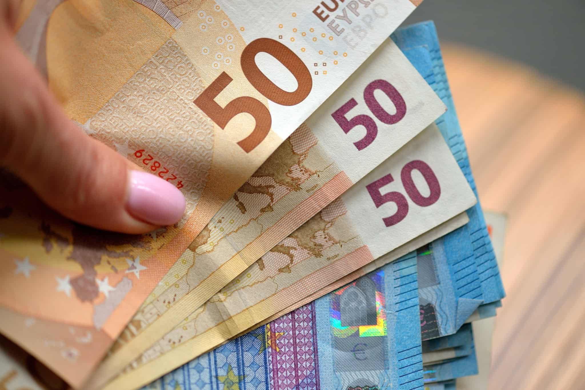 Mão de mulher com várias notas de 50 e 20 euros