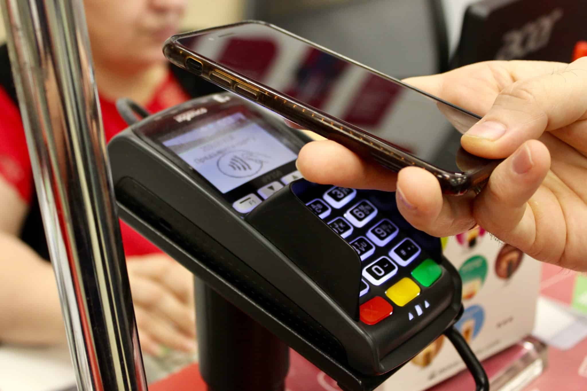 Pessoa paga uma conta com o telemóvel através do terminal