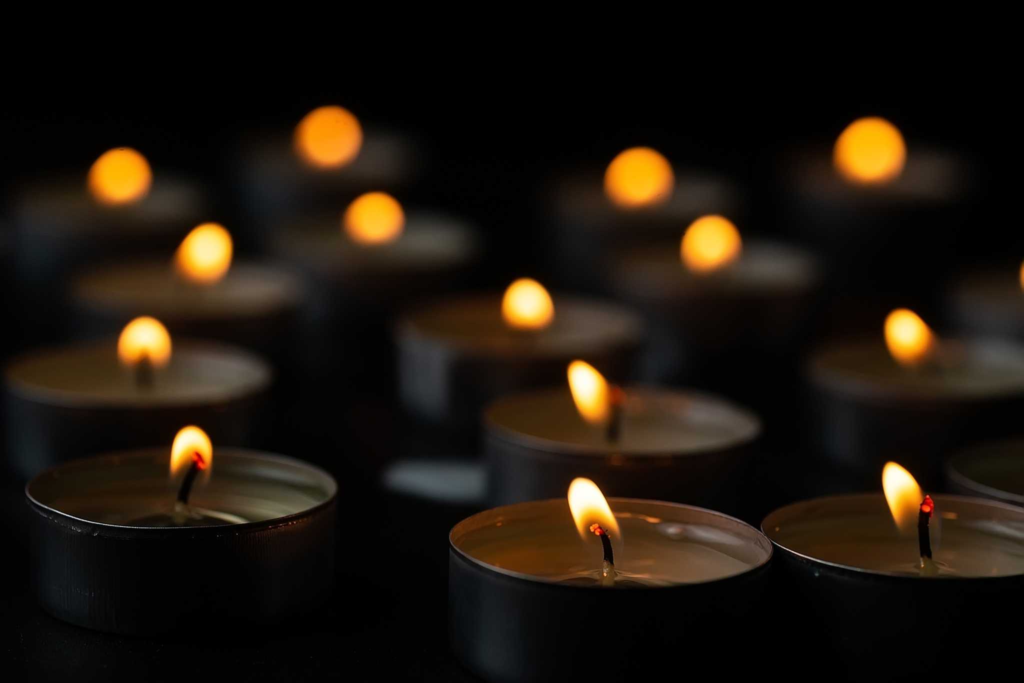 várias velas acesas, sobre uma mesa e um fundo escuro