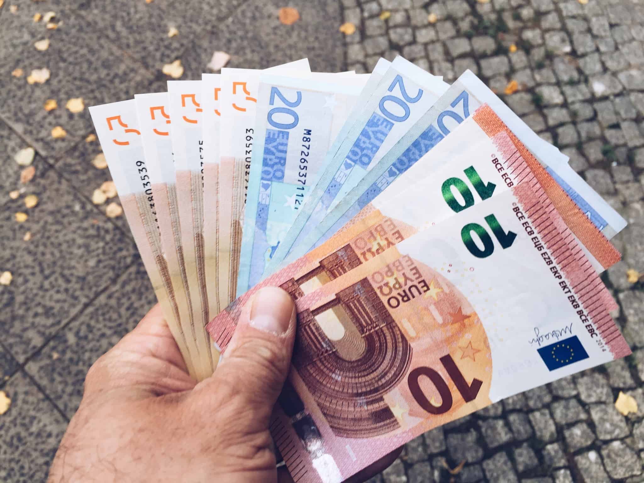 Mão de homem a segurar várias notas de euro