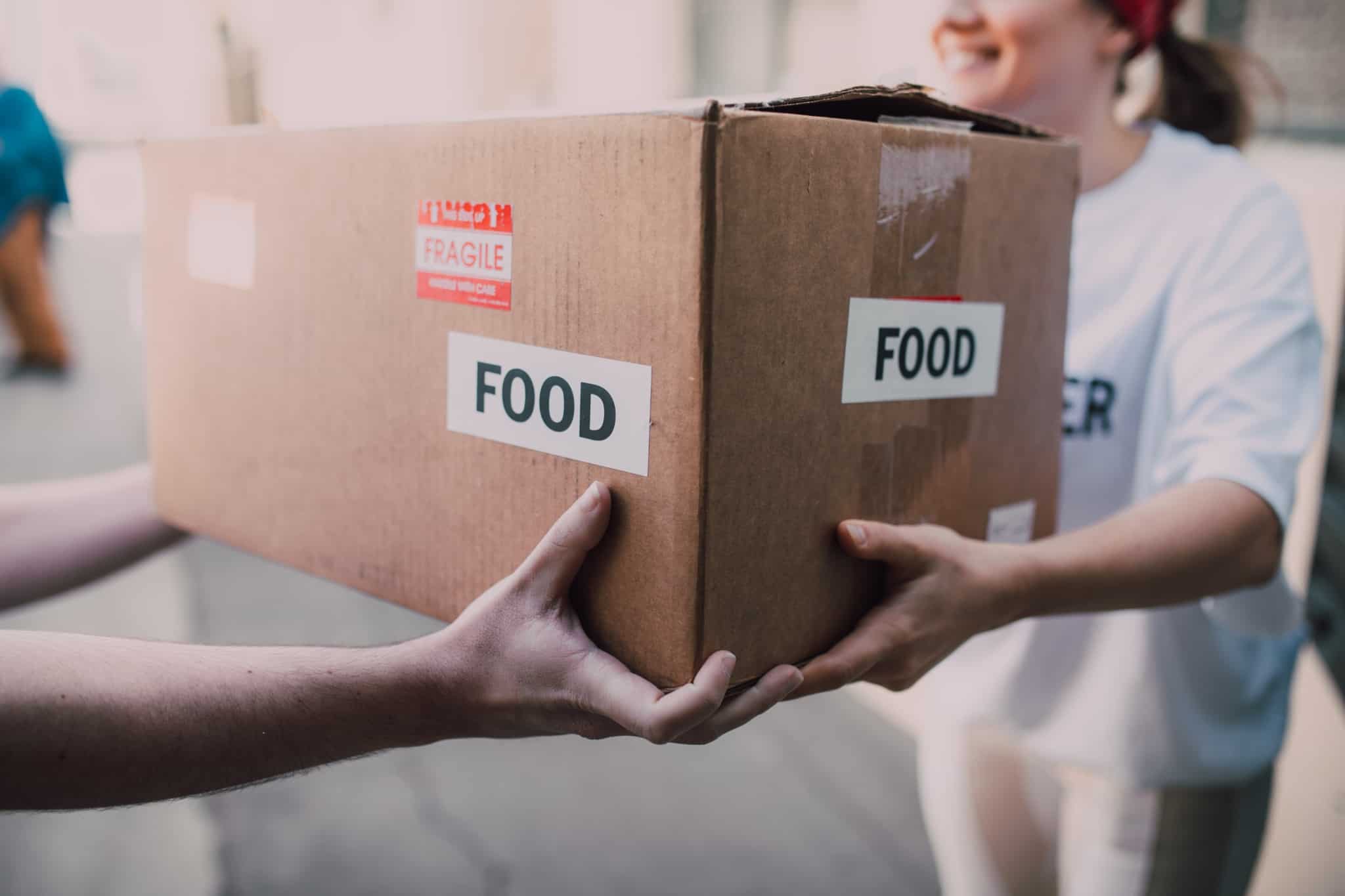 uma pessoa a doar uma caixa de comida a outra