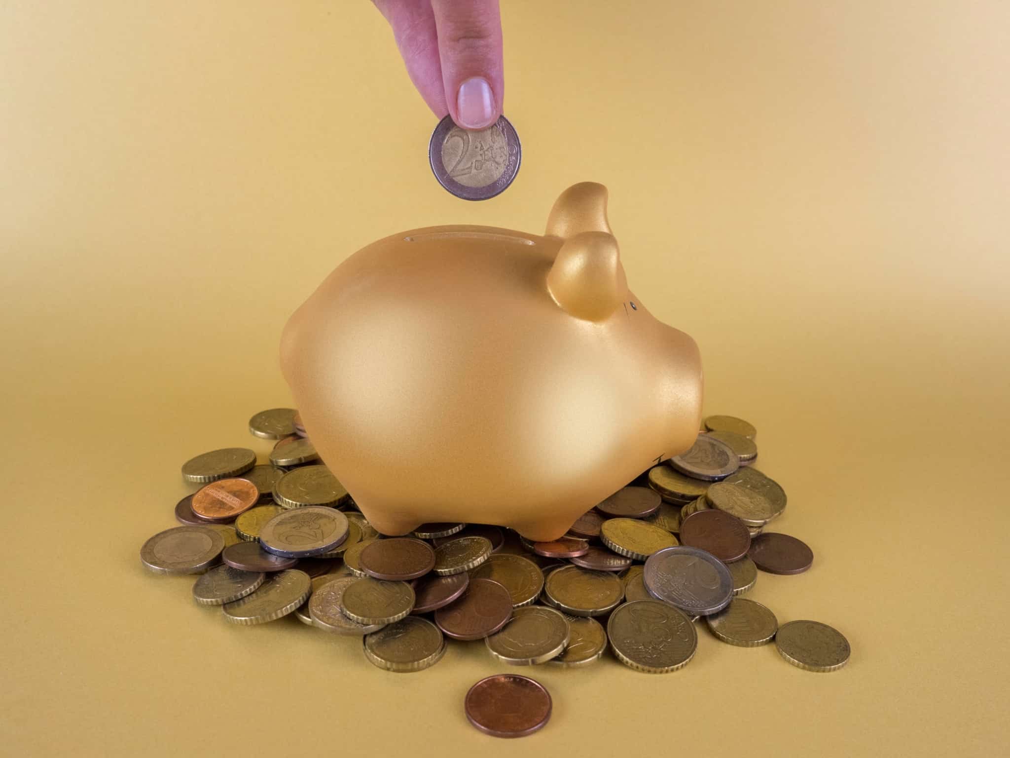 Um porquinho mealheiro dourado rodeado de moedas de euro