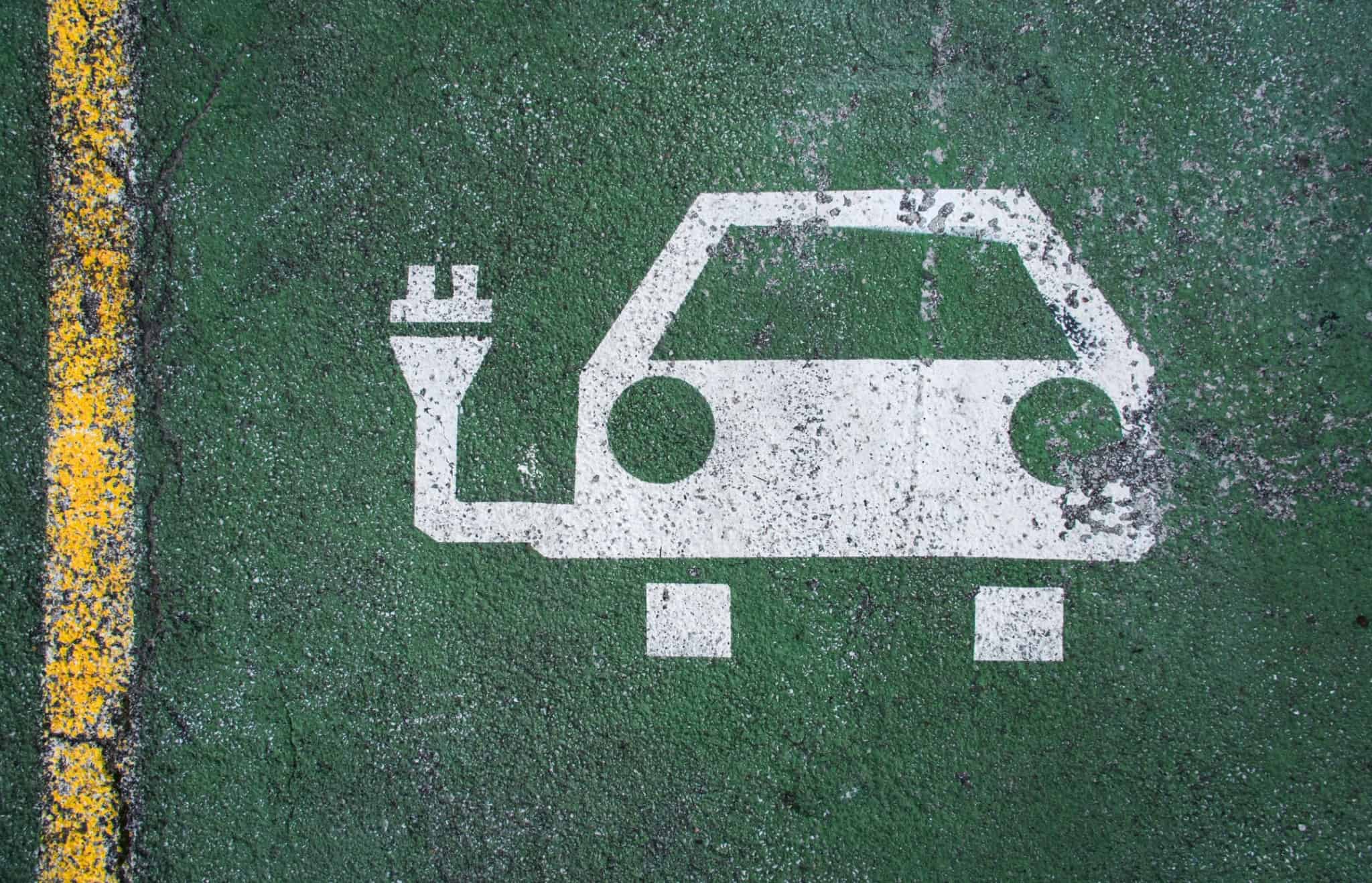 Desenho de um carro ligado a uma ficha elétrica pintado no chão a identificar uma zona de carregamentos de carros elétricos