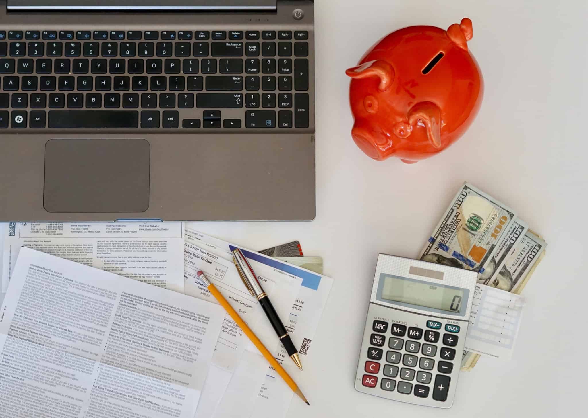uma mesa com notas, calculadora, faturas e computador
