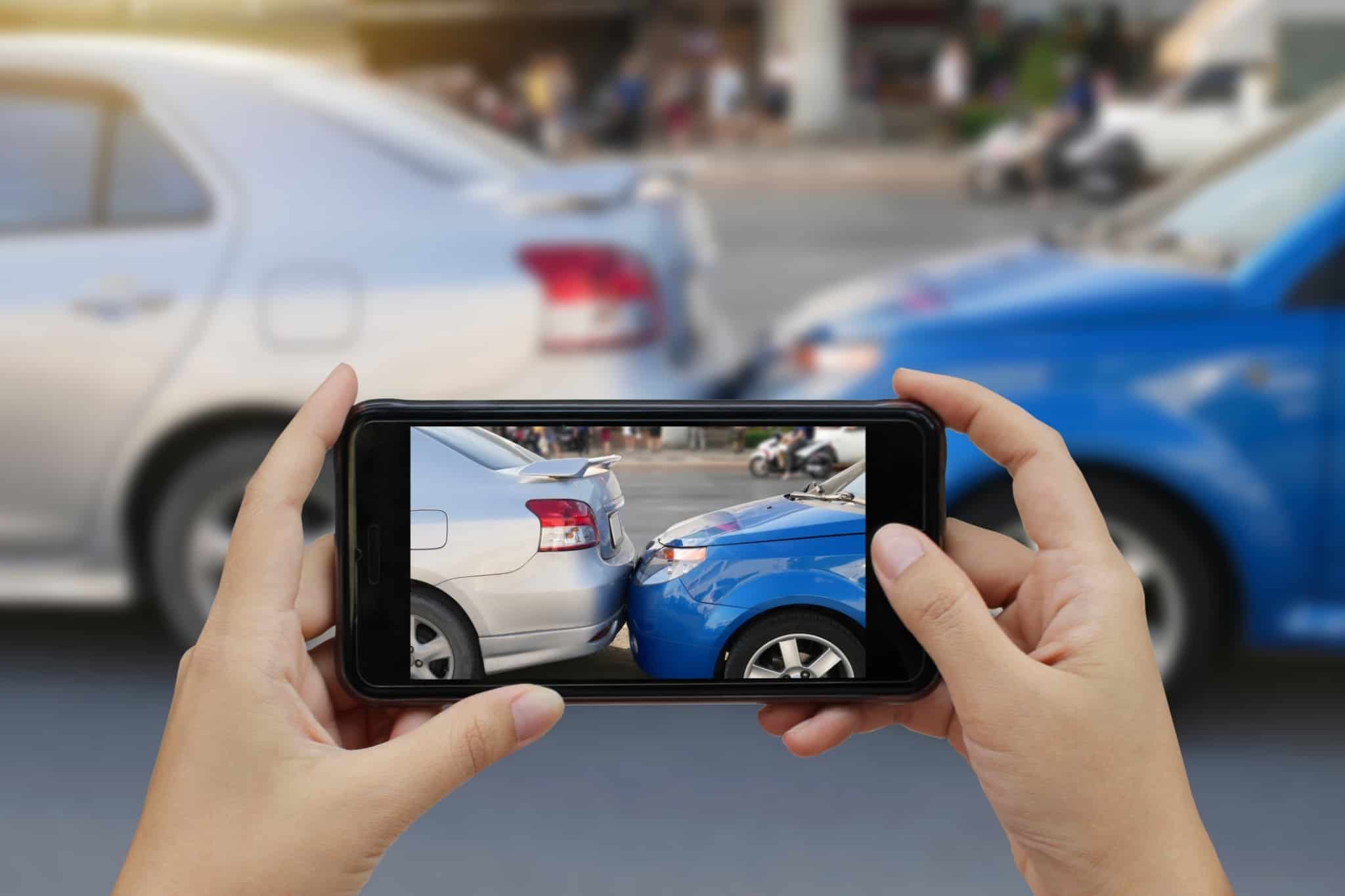 Pessoa tira fotografia com o seu telemóvel a um acidente entre carros