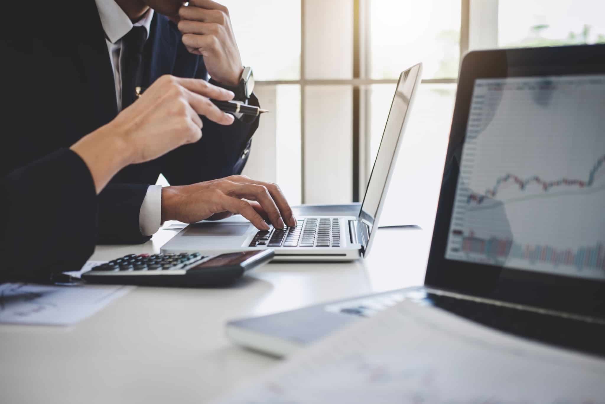dois colegas de trabalho analisam dados num computador