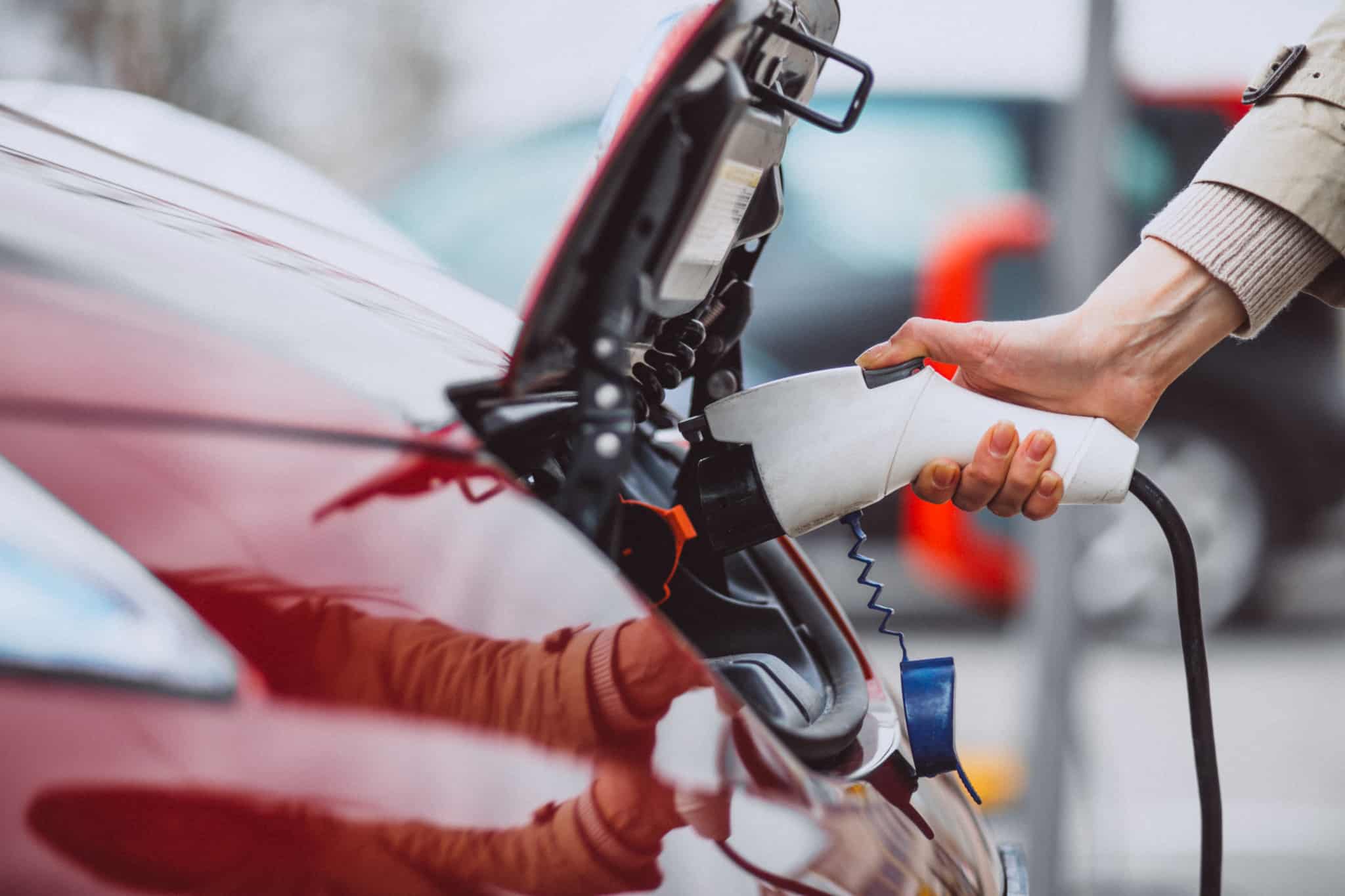 Mulher carrega o seu carro elétrico