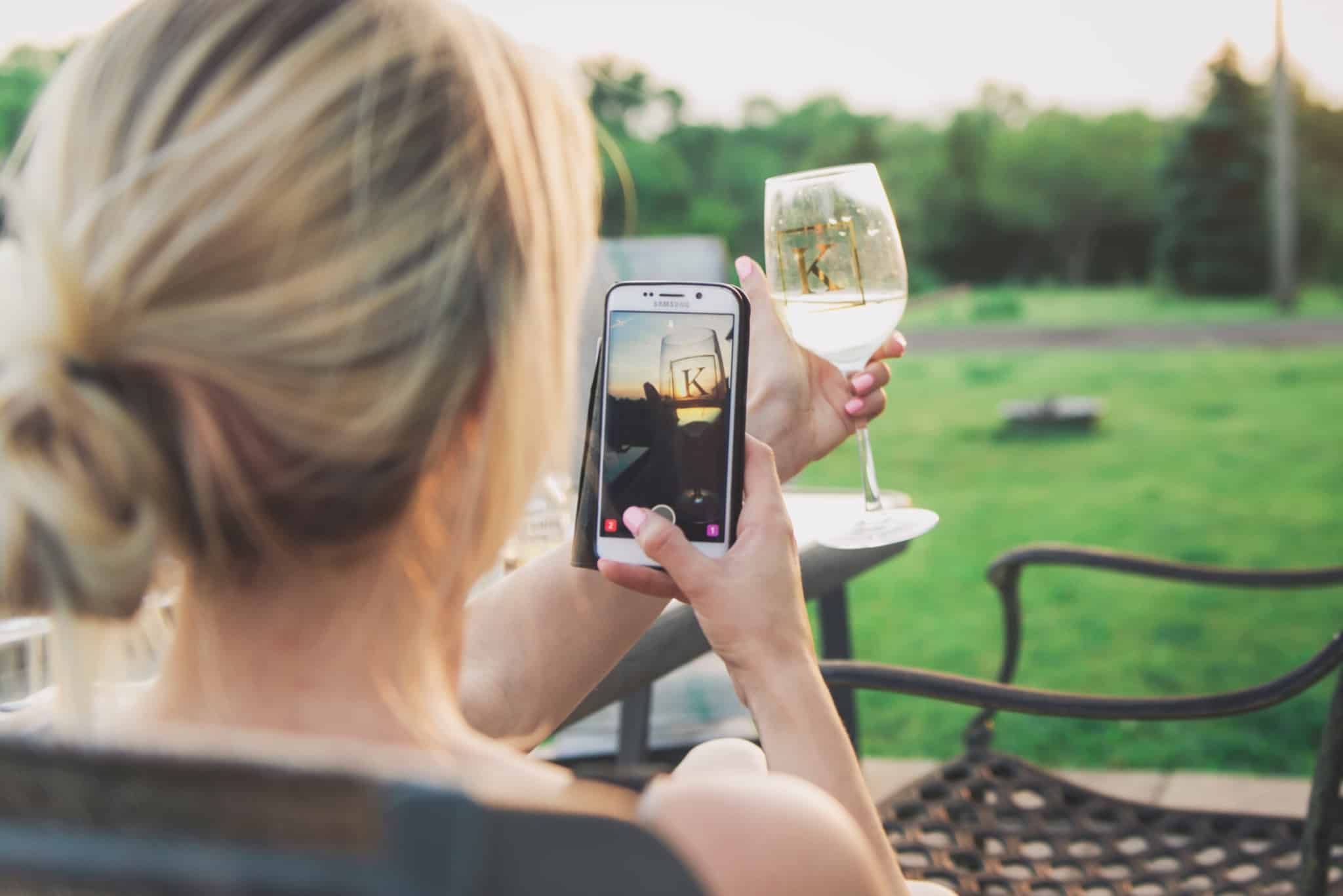 rapariga a tirar foto a um copo de vinho no snapchat