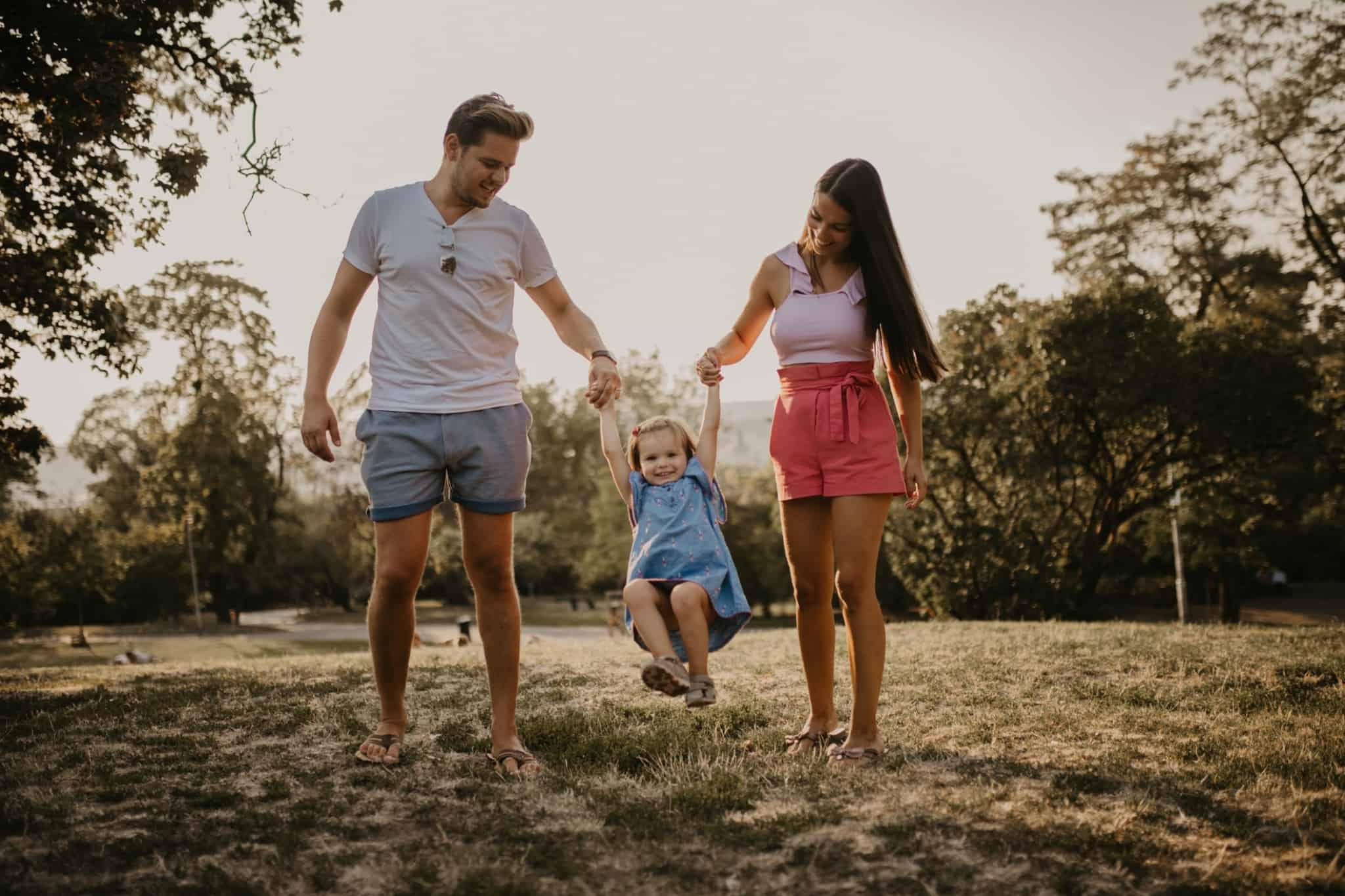 Família, composta pelo pai, pela mãe e por uma criança, caminham juntos enquanto brincam
