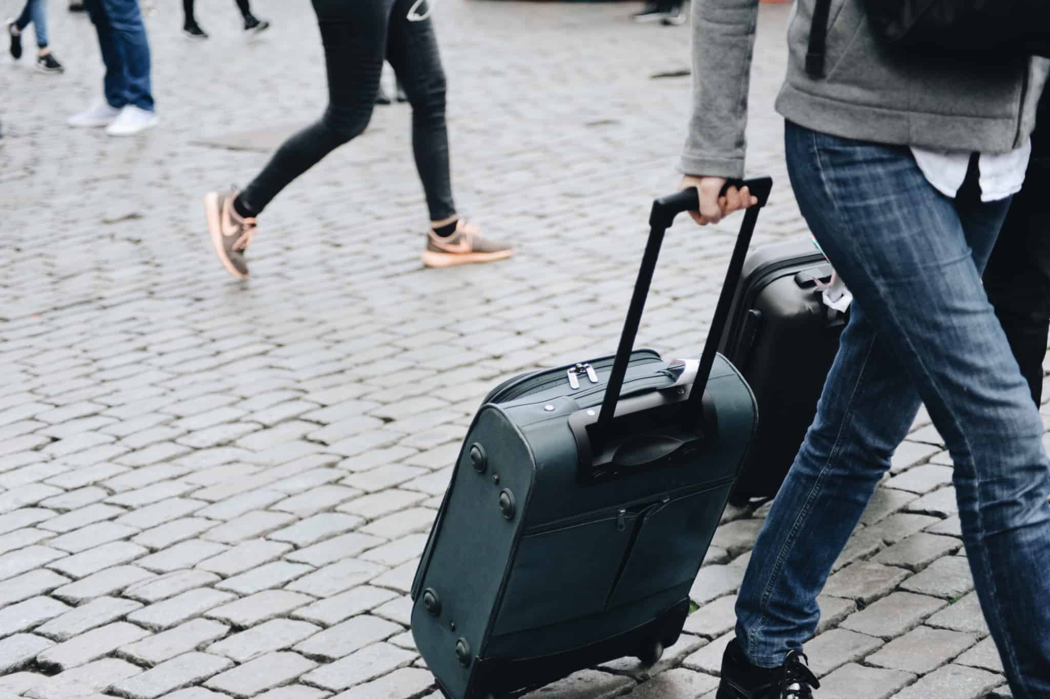 Viajante arrasta uma mala de viagem por uma rua empedrada